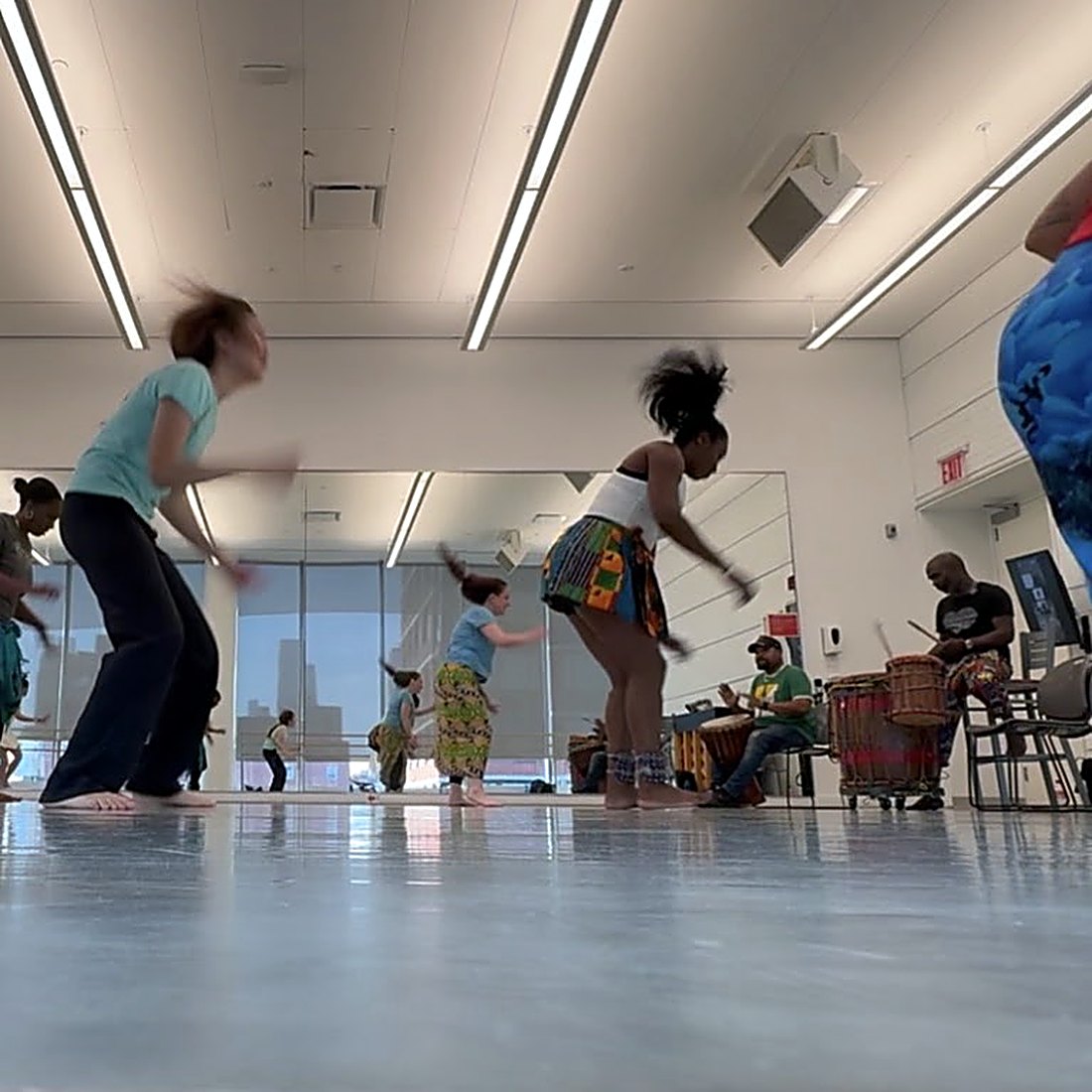 West African dance class in motion with live drummers
